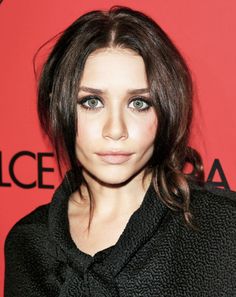 a close up of a person wearing a black shirt and hair in a pony tail