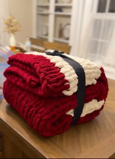 a stack of red and white blankets sitting on top of a wooden table