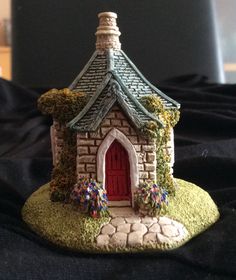 a small house with a red door on top of a black cloth covered tablecloth