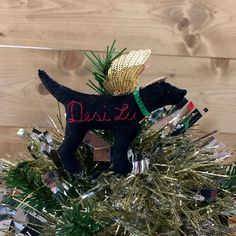 a black dog ornament sitting on top of a christmas tree covered in tinsel