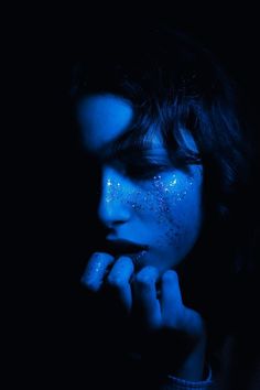 a woman with blue face paint in the dark