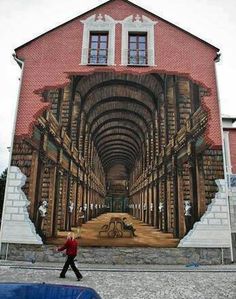 a person walking in front of a building with a mural on it