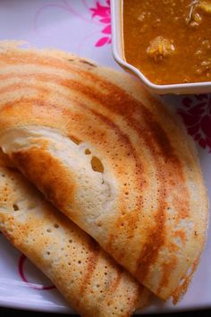 two pita breads sitting on top of a plate next to a bowl of soup