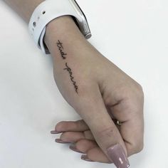 a woman's hand with a small tattoo on the left side of her arm