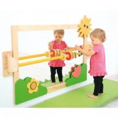 two children playing with wooden toys in front of a mirror