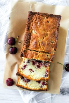 sliced loaf of fruit bread with fresh cherries on the side and two slices cut off