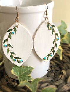 Hand painted Delicate Ceramic Clay Earrings  Please note that each pair are handcrafted, making each one unique to you.  Lightweight Clay  Color- Ivory, Green Swarovski crystals for detail  Approximately 3 inches in length  Glossy finish  Avoid dropping earrings, as this may result in breaking.  Hooks- Nickel and lead free. Hypoallergenic friendly ♥️ Painted Clay Earrings, Hand Painted Earrings Wood, Dropping Earrings, Fabric Jewellery, Clay Color, Earrings Polymer, Earrings Wood, Hand Painted Earrings, Painted Earrings