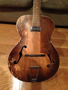 an old guitar sitting on top of a wooden floor