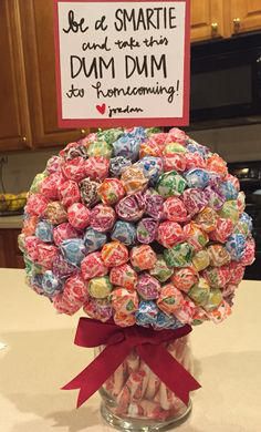 a vase filled with lots of candy sitting on top of a counter next to a sign