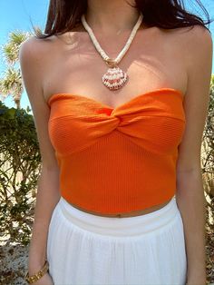 Our Hot Shot Knit Tube Top in Orange is a major head turner moment! This top features super soft ribbed knit material, twist front bandeau style, and crop length. Style this top with all your fave shorts, skirts or linen pants for a chicest look! Styled with our "Island Time Shell Beaded Necklace" Content: 45% Polyester 32% Viscose 23% Nylon Fit: TTS Model wearing size: Small Model sizing: 0-2 top, 24" bottoms | Height: 5'3" Orange Top Outfit Summer, Necklace Content, Orange Top Outfit, Orange Tube Top, Shell Beaded Necklace, Gameday Fits, Knit Tube Top, Top Summer Outfits, Shell Beads Necklace