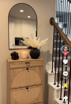 a wooden cabinet sitting next to a stair case with a mirror on top of it