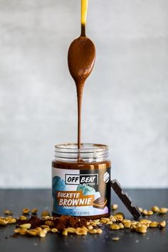 a spoon full of peanut butter and some peanuts