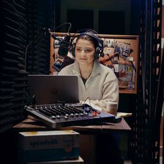 a woman wearing headphones sitting in front of a laptop computer on top of a desk