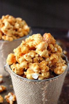 two cups filled with caramel popcorn on top of a table