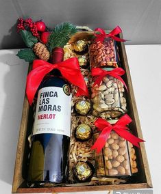 a bottle of wine in a wooden box filled with nuts and other holiday food items