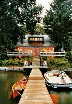 two boats are docked at the end of a dock with a house in the background