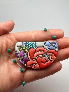 a hand is holding a colorful flower painted on it's palm with beaded bracelets