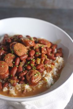 a white bowl filled with beans and rice on top of a table next to a napkin