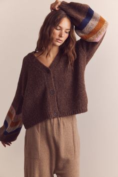 a woman is wearing a brown sweater and pants