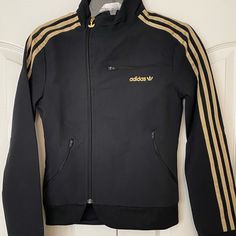 New Adidas Asymmetrical Women’s Jacket In Black With Gold Metallic Stripes. Trefoil Embroidered In Gold Metallic. 2 Zippered Pockets. Size: Xs L: 22.5. Chest: 15” Shoulder: 4.5” Sleeve: 24” Shell: 94% Nylon 6% Spandex Lining: 100% Polyester Adidas Fitted Long Sleeve Outerwear, Fitted Long Sleeve Adidas Outerwear, Fitted Adidas Winter Track Jacket, Adidas Fitted Hooded Outerwear, Fitted Adidas Track Jacket For Winter, Adidas Fitted Outerwear For Fall, Gold Adidas, Adidas Jackets, Utility Jacket