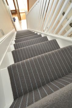 the stairs are lined with gray carpet and white railings