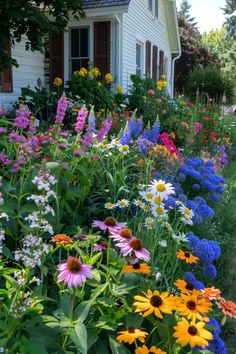 colorful flowers line the side of a white house