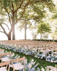 rows of chairs with blue and white flowers in the grass at a wedding ceremony under trees