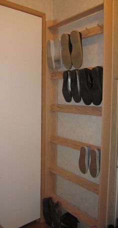 shoes are lined up on the shelves next to a closet door in a small room