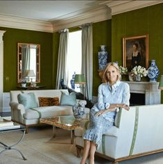 a woman sitting on a couch in a living room with green walls and white furniture