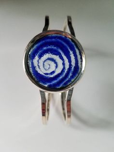 This unique bracelet is made with a hand designed and fired copper enameled disc set into a silver plated bangle. The disc is approximately 1 inch diameter and I've used cobalt blue enamel over white enamel. I've drawn a spiral design into the enamel. The bracelet fits all sizes. It is nickel and lead free. Adjustable Enamel Cuff Bracelet As Gift, Adjustable Enamel Bangle As Gift, Adjustable Enamel Bangle As A Gift, Adjustable Enamel Cuff Bracelet For Gift, Adjustable Enamel Bangle For Gift, Unique Blue Nickel-free Cuff Bracelet, Blue Sterling Silver Round Cuff Bracelet, Adjustable Round Blue Bangle, Unique Blue Bangle