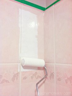 a white toilet paper dispenser mounted to the side of a pink tiled wall