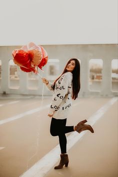 a woman holding two red balloons in her hand