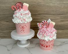 two cupcakes decorated with candy canes and candies