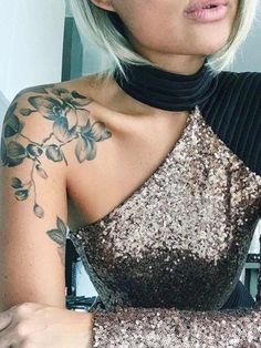 a woman with tattoos on her arm and shoulder is looking at the camera while wearing a dress