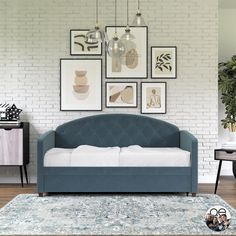 a blue couch sitting in front of a white brick wall with pictures on the wall