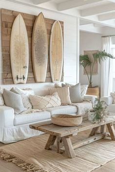 a living room filled with white furniture and surfboards on the wall above it's windows