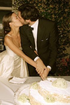 a bride and groom are kissing in front of a wedding cake that is on top of a table