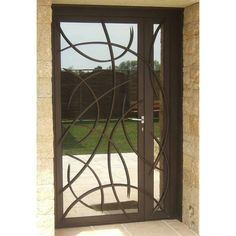 an iron door with decorative glass in front of a stone wall and grassy area behind it