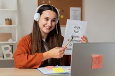 a girl wearing headphones holding up a piece of paper