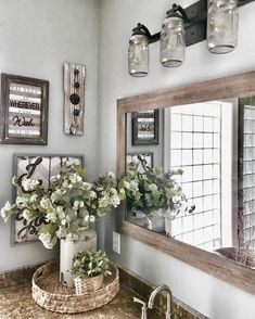 a bathroom with pictures on the wall and a vase full of flowers in front of it