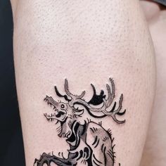 a black and white tattoo on the leg of a woman's thigh with an image of a dragon