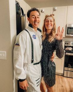 a man and woman are posing for a photo in the kitchen with their hands up