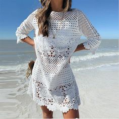 a woman is standing on the beach wearing a white crochet cover - up