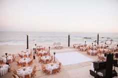 an outdoor wedding setup on the beach with tables and chairs set up in front of the ocean