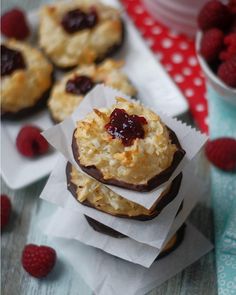 raspberry filled cookies on top of white paper next to fresh raspberries