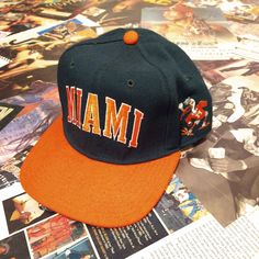 a hat with the word miami on it is laying on top of magazines and papers