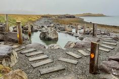 there are many stepping steps leading to the water in this rocky area that is surrounded by rocks and grass