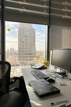 a desk with a computer, keyboard and mouse on it in front of a large window