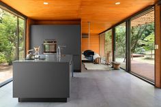 an open kitchen and dining area with wood ceilinging, glass walls, and floor to ceiling windows