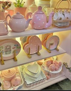 the shelves are filled with pink and white teapots, plates, and other decorative items